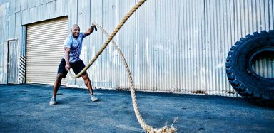 A man working out outside with heavy ropes.